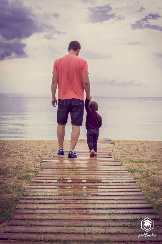Pai e filhinha contemplando o mar